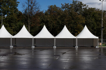 Free white pavilions for retail and events on a paved area in the park.