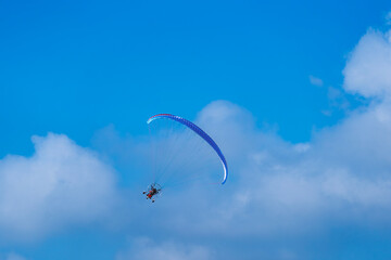 Flying with paramotor in the blue sky - Man riding paramotor in the blue sky background
