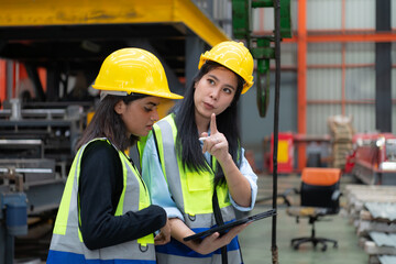 Two female engineers working together in metal sheet factory. This is a freight transportation and distribution warehouse. Industrial and industrial workers concept