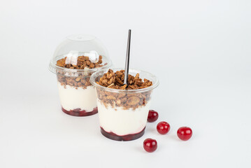 Yogurt with granola flakes and fruits in a plastic cup to go