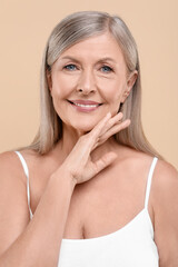 Portrait of beautiful senior woman on beige background