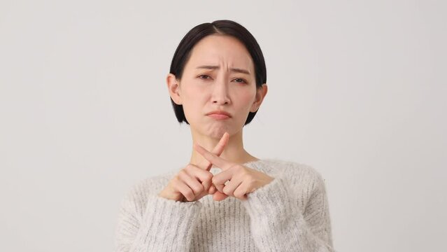 指でばつ印のジェスチャーをする中年女性　白背景