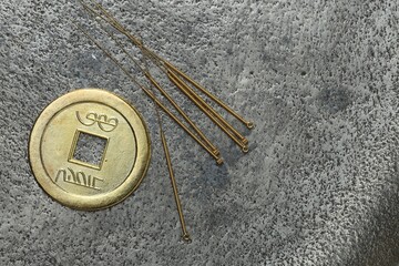 Acupuncture needles and ancient coin on grey textured table, flat lay. Space for text