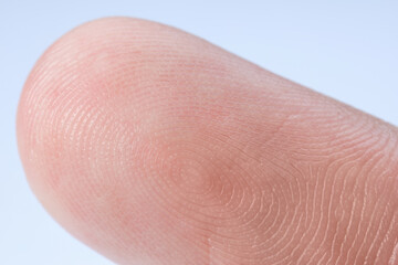 Fototapeta premium Finger with friction ridges on light blue background, macro view
