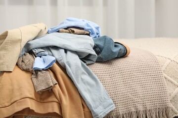 Pile of different clothes on bed at home