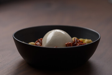 Pesto conchiglie with sundried tomatoes and burrata cheese served in black bowl