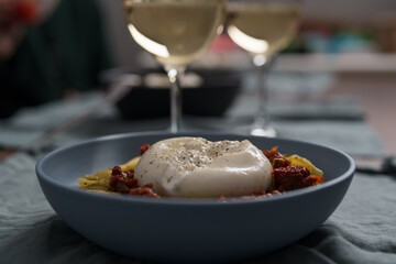 Pesto conchiglie with sundried tomatoes and burrata cheese served in blue bowl