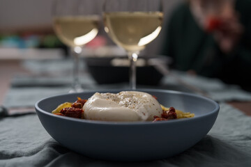 Pesto conchiglie with sundried tomatoes and burrata cheese served in blue bowl
