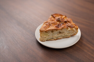 A piece of charlotte apple pie on a saucer on walnut table