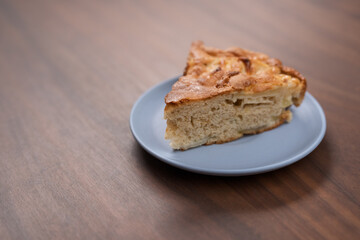 A piece of charlotte apple pie on a saucer on walnut table