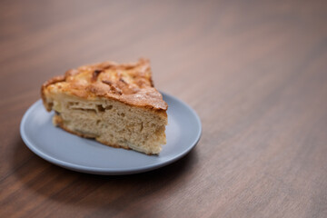 A piece of charlotte apple pie on a saucer on walnut table