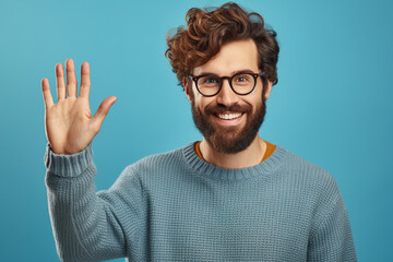 Young handsome man with beard wearing casual sweater and glasses over blue background Waiving saying hello happy and smiling, friendly welcome gesture - obrazy, fototapety, plakaty