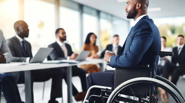 Disabled businessman in a wheelchair in office, having conversion with colleague