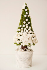 A small Christmas tree. Handmade, made of moss. Decorations from threads. Christmas spirit at home.