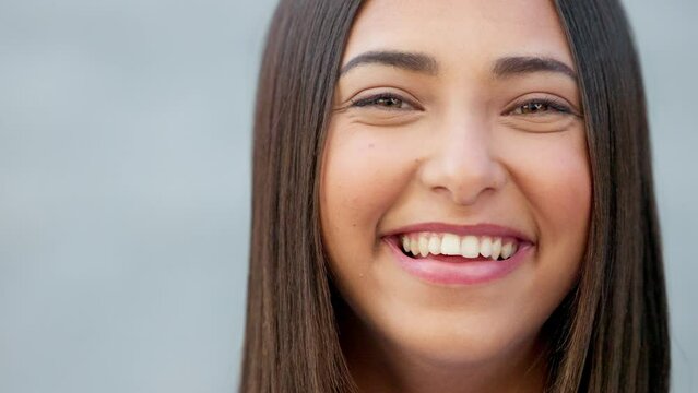 Closeup of laughing woman showing cheerful facial expression isolated on a grey wall background with copy space. Portrait, headshot or face of smiling, fun and trendy student giggling at funny joke