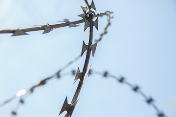 barbed wire spiral through which the blue sky is visible. selective focus.