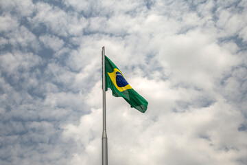 Uma Bandeira do Brasil tremulando ao vento em um dia nublado.