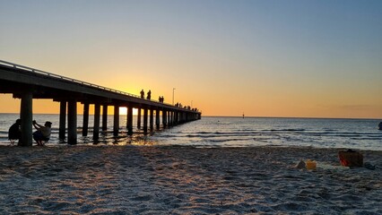 Sandy beach and pier against the background of the sunset.