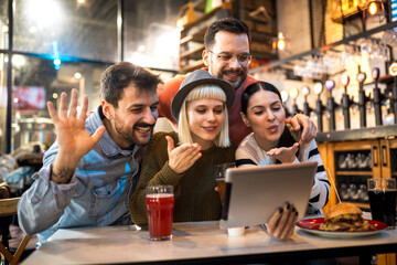 Young friends looking at digital tablet while sitting in cafe.