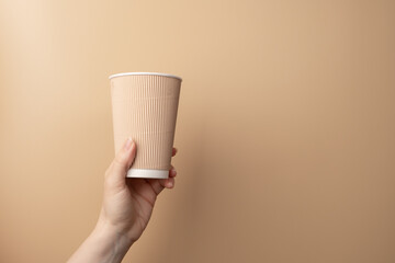 Coffee to go, a hand carrying a hot takeaway drink. Coffee in a cardboard cup