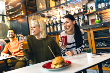 Smiling young friends drinking craft beer in pub