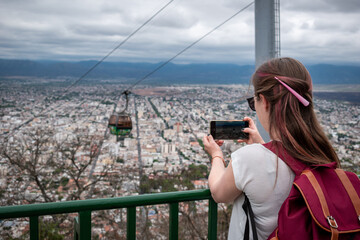 Mujer turista tomando fotos desde el mirador del Cerro San Bernardo, en la ciudad de Salta - obrazy, fototapety, plakaty