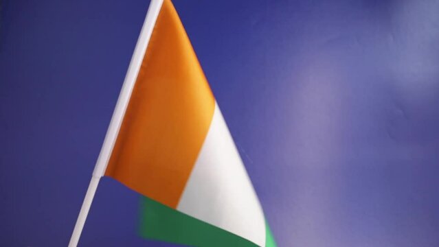 cote d'ivoire flag in hand on a blue background, independence national day of cote d'ivoire, country freedom, patriotism