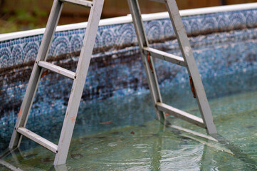 folding ladder in swimming pool, outdoor shot, no people 