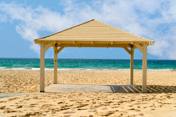 Beach canopy from the sun, without people on the shore of the beach at sea, in the background