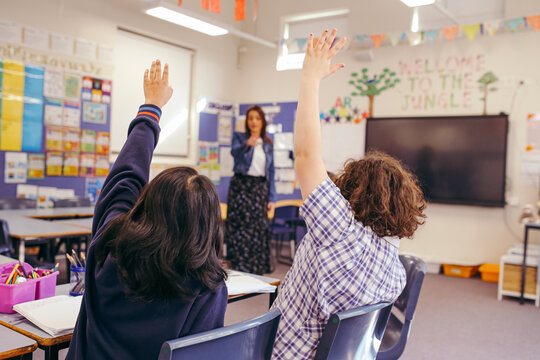 Students in a classroom with their hands up