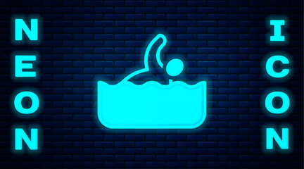 Glowing neon Swimmer athlete icon isolated on brick wall background. Vector
