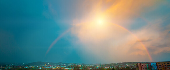 Colorful atmospheric panoramic landscape with a dramatic sky and a rainbow.