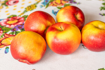 beautifully ripe apples lying on an embroidered tablecloth, healthy and tasty fruit, natural food