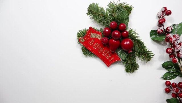 WISHES written in Italian with Christmas decorations. Right side a branch with pine cones, red berries and snow, copy space.