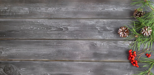 Fototapeta premium Wooden background with spruce branches, cones and rowan berries. Natural Christmas decor