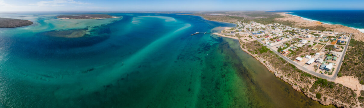 Aerial panorama view of a small coastal town on the edge of a wide blue bay