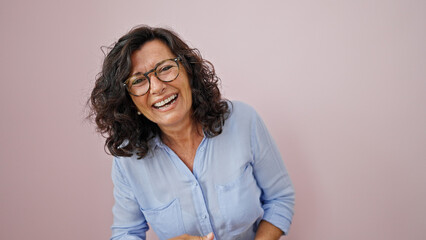 Middle age hispanic woman laughing a lot over isolated pink background