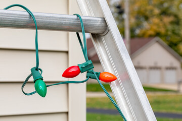 Christmas string lights hanging on ladder rung outside of house. Holiday lighting decorating,...