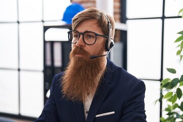 Young redhead man call center agent working with relaxed expression at office