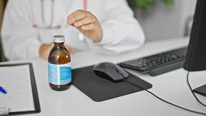 Young beautiful hispanic woman doctor using computer holding medication bottle at clinic