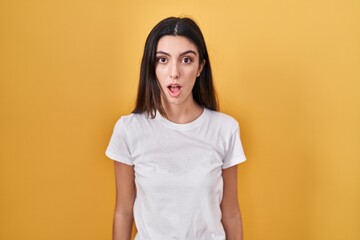 Obraz premium Young beautiful woman standing over yellow background afraid and shocked with surprise and amazed expression, fear and excited face.