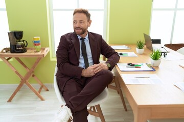 Middle age man business worker smiling confident sitting on table at office