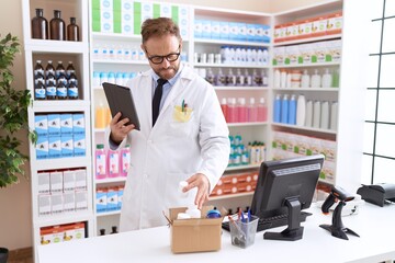 Fototapeta na wymiar Middle age man pharmacist using touchpad holding pills bottle at pharmacy