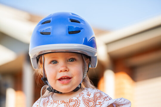 Toddler girl outside wearing bike helmet for safety while riding