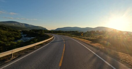 Driving a Car on a Road in Norway at dawn.
