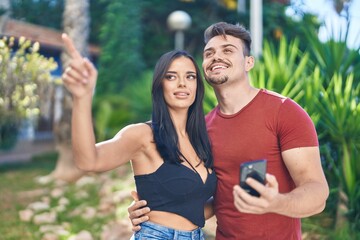 Man and woman couple smiling confident using smartphone at park