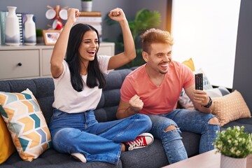 Man and woman couple watching soccer match sitting on sofa at home