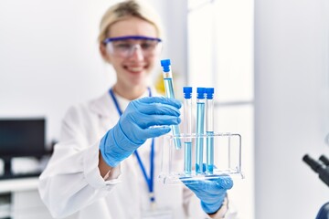 Fototapeta premium Young blonde woman scientist analysing test tubes at laboratory