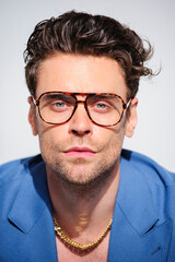 Obraz premium Portrait of stylish brunette model in eyeglasses and blue jacket isolated on grey