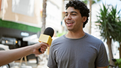 Young latin man having interview smiling at street